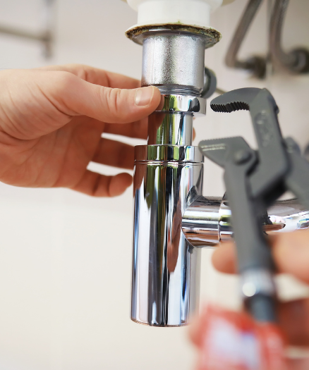 A person fixing a faucet with a wrench