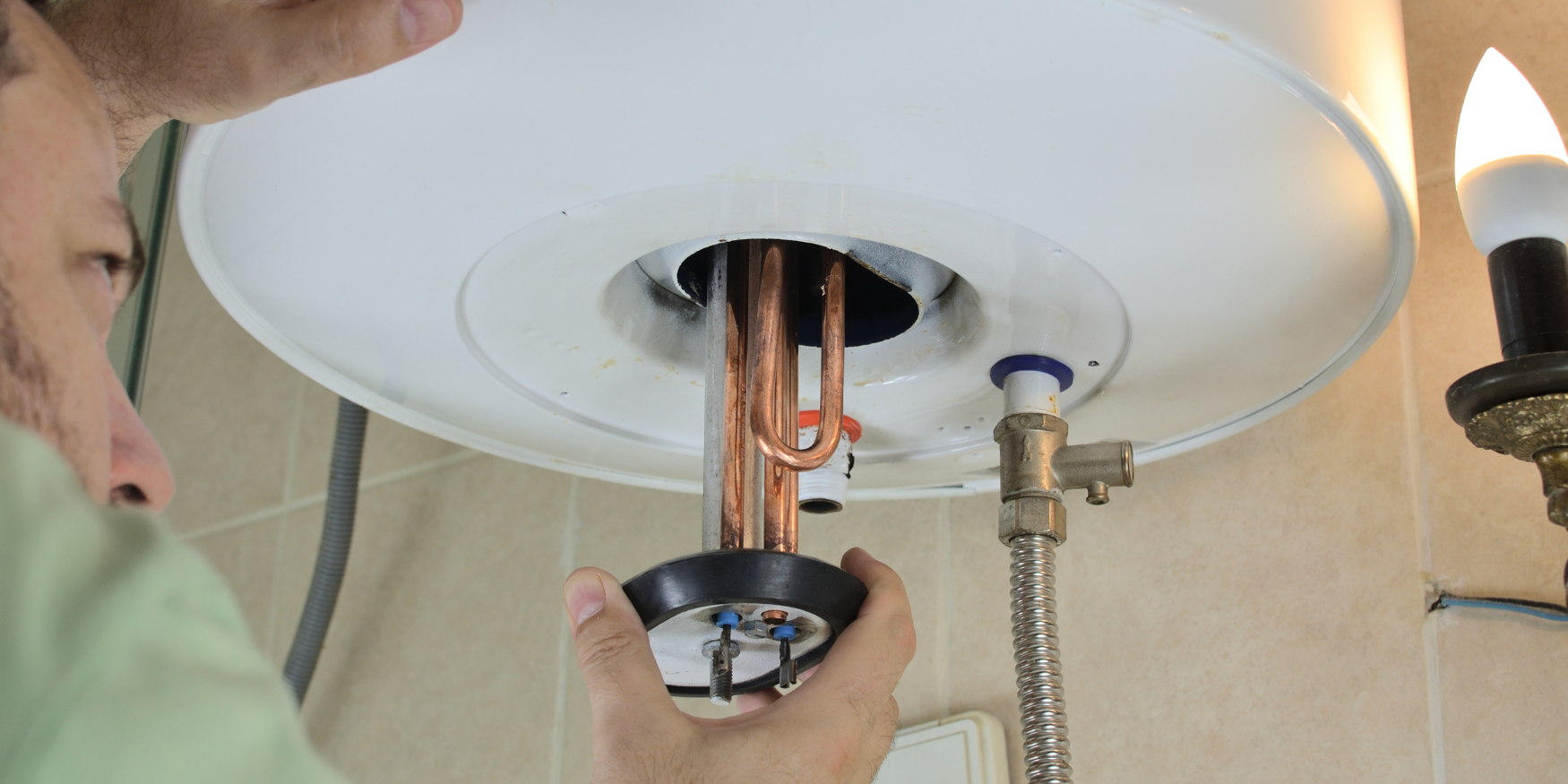 A man fixing a light fixture in a bathroom