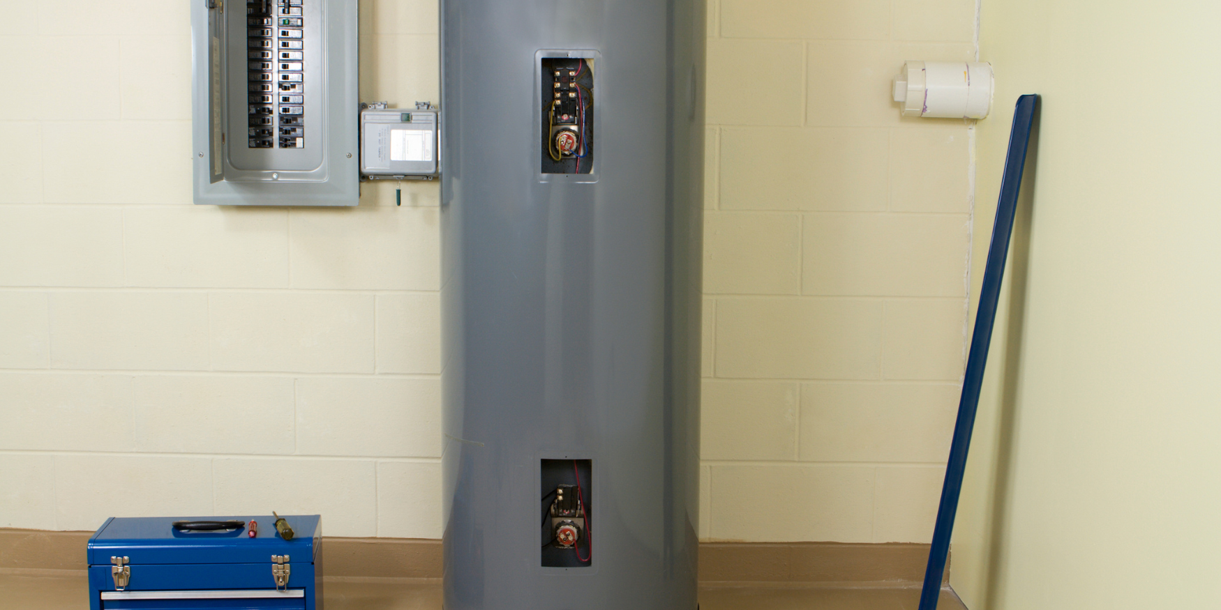 A water heater sitting next to a blue toolbox